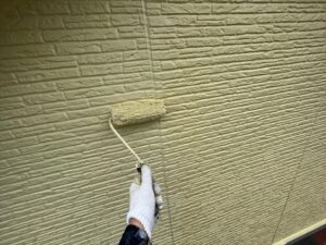 春日部市にて外壁塗装工事の上塗り作業中の写真