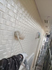 桶川市にて外壁塗装の上塗り作業中の写真