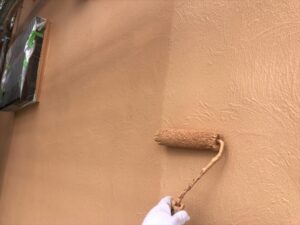 春日部市にて外壁塗装の上塗り作業中の写真