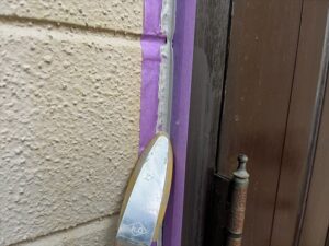 蓮田市にて玄関ドアとの取り合い部に打ち込んだコーキング材をヘラで押える工程
